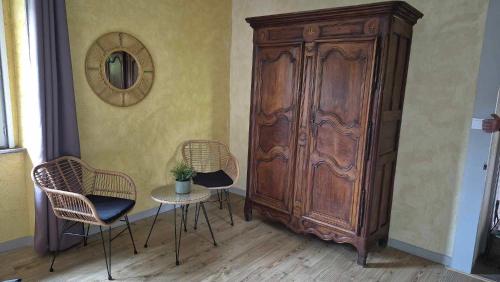 a room with two chairs and a large wooden cabinet at Nature en petite montagne in Arinthod