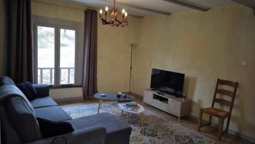 a living room with a blue couch and a tv at Nature en petite montagne in Arinthod