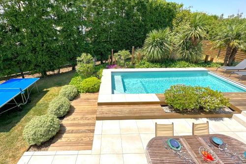 - une piscine dans un jardin avec une table et des chaises dans l'établissement La Céleste-Villa standing avec piscine et jardin, à Saint-Herblain
