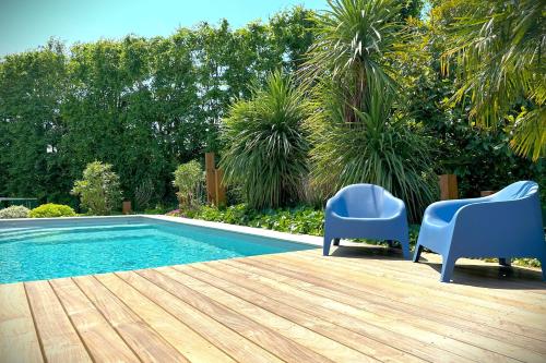 - deux chaises bleues installées à côté de la piscine dans l'établissement La Céleste-Villa standing avec piscine et jardin, à Saint-Herblain