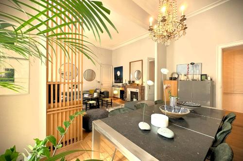 une salle à manger avec une table, des chaises et un lustre dans l'établissement L'Illustre-Elegant appartement hypercentre-Balcon, à Nantes