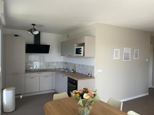 une cuisine avec une table avec un vase de fleurs dessus dans l'établissement Nouveau T3 à 500 m de la plage, à Berck-sur-Mer