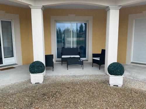 a porch of a house with chairs and a table at Une chambre pour deux avec vue sur la piscine in Le Pizou