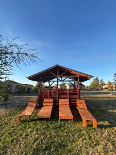 a picnic shelter with wooden benches in a field at Cabañas Campestres Inés in Chillán