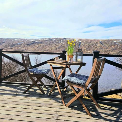 a table and two chairs on a deck with a view of the water at Lakefront cottage with jacuzzi in Borgarnes