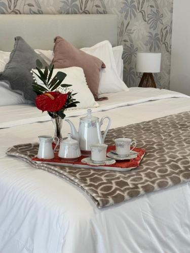 a tray with tea sets and flowers on a bed at Bella Casa Bed and Breakfast in Ponta Delgada