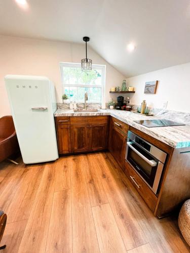 a kitchen with a white refrigerator and wooden floors at The Guesthouse with Pool and Hot Tub Near Casinos in Reno