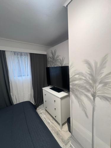 a bedroom with a tv and a palm tree painted on the wall at Artistic & cozy ! Just 5' to seaside in Athens