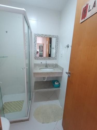 a bathroom with a sink and a shower and a mirror at Residencial Verano 105C in Guarajuba