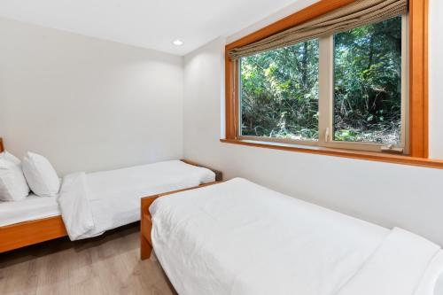 two beds in a room with a window at The Cabins at Terrace Beach in Ucluelet