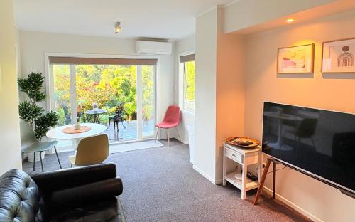 a living room with a couch and a television at Spacious & Secluded Bush-View Suite in Kohimarama in Auckland