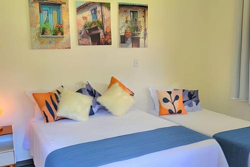 two beds in a room with paintings on the wall at Bosque do Itaoca - Beira do Rio, Lago, Mata Nativa in Guararema
