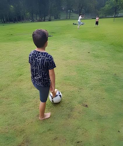 a young boy playing with a soccer ball in a field at Bosque do Itaoca - Beira do Rio, Lago, Mata Nativa in Guararema