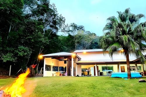 a house with a fire in front of it at Bosque do Itaoca - Beira do Rio, Lago, Mata Nativa in Guararema