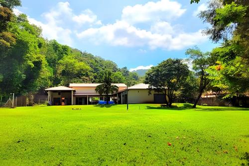 a building with a large green field in front of it at Bosque do Itaoca - Beira do Rio, Lago, Mata Nativa in Guararema