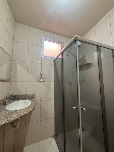 Un baño con ducha de cristal y lavabo. en Recanto dos Monteiros, en Vila Velha