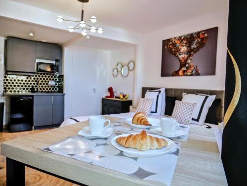 - une table avec des croissants et des tasses dans l'établissement Nid douillet tout équipé, 6 min château d'Amboise, à Amboise