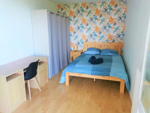 - une chambre avec un lit doté d'une couverture bleue et d'un bureau dans l'établissement Spacious apartment bellevue, à Brest