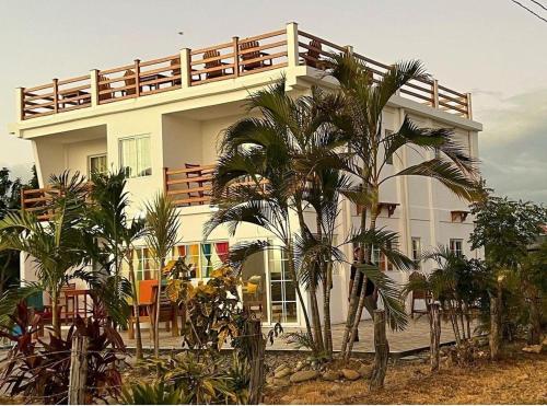 a white building with palm trees in front of it at Popoyo Beach Home in Tola