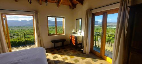 a bedroom with a bed and a balcony with windows at Felicita Country Lodge in Stanford