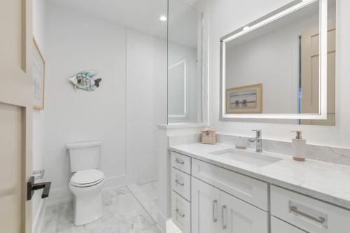 a white bathroom with a toilet and a sink at Sunkised Sands Flagler Beach in Flagler Beach