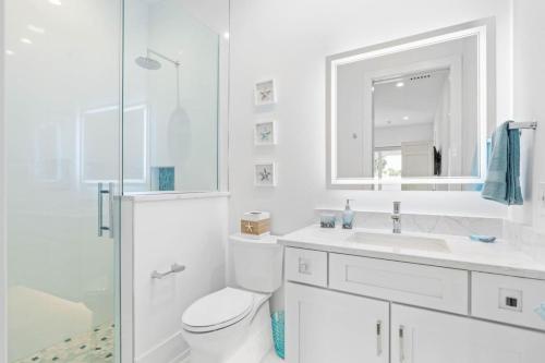 a white bathroom with a toilet and a sink at Sunkised Sands Flagler Beach in Flagler Beach