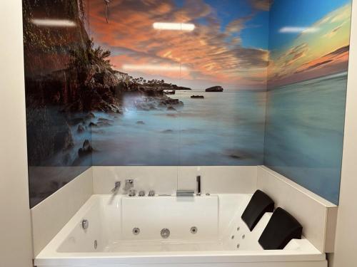 a bathroom with a bath tub with a painting on the wall at Flower Deluxe Bajo con Jardin 6083 in Noja