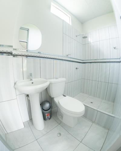 a white bathroom with a toilet and a sink at Las Cascadas Resort in Naranjillo
