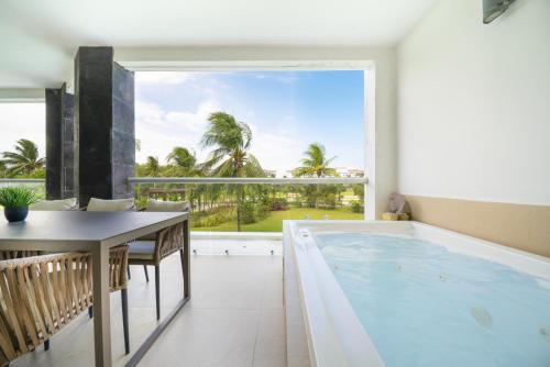 une grande piscine intérieure avec une table et une grande fenêtre dans l'établissement Luxury 2 BR Condo with tub & Infinity Pool - Beach Side At Mareazul - Sirenita G, à Playa del Carmen