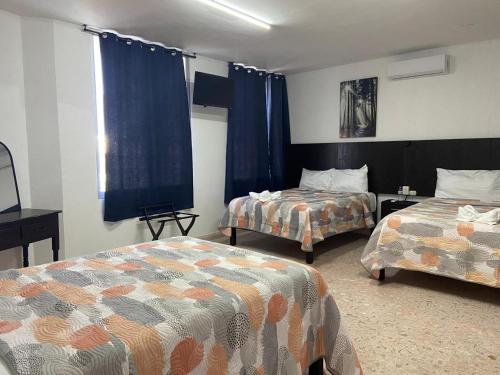 a hotel room with two beds and blue curtains at Casa Guadalupe in Campeche