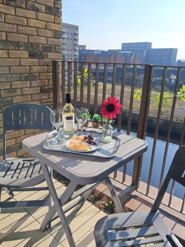 a table with a bottle of wine and a plate of food at 2Bed 2Bath Private Balcony, Relaxing Waterfront View Apt, Parking FREE WiFi 10mins Media City, Salford Quays, Old Trafford, City Centre in Manchester