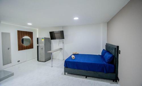 a bedroom with a blue bed and a refrigerator at Hotel Boutique Casa Teresita in Medellín