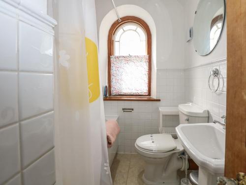 a white bathroom with a toilet and a sink at Captain's Rest in Porthmadog