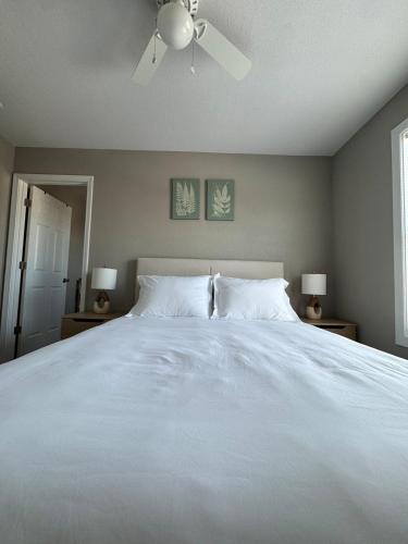 a bedroom with a white bed with a ceiling fan at Newly built 3 level home 2 minute drive to UCM in Warrensburg