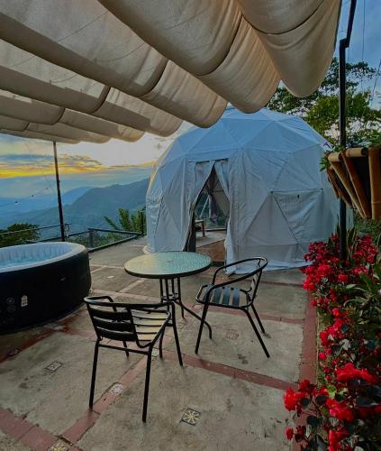 a patio with a table and chairs and a tent at Andino Glamping in La Peña