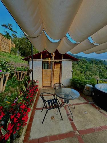 a patio with a table and chairs under an umbrella at Andino Glamping in La Peña