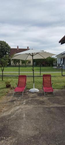 two chairs sitting under an umbrella in a parking lot at Seosko turističko domaćinstvo Stanković in Arandjelovac