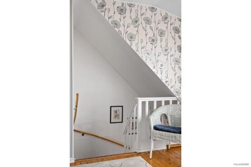 a room with a staircase with a chair and wallpaper at Lakefront house on Skåne's largest island in Ivö