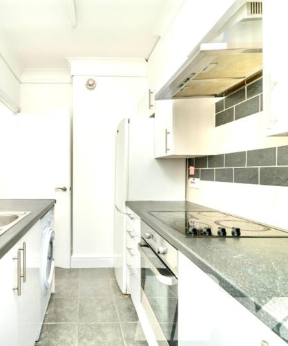 a kitchen with white cabinets and gray counter tops at Regents Park Camden St Johns Wood in London