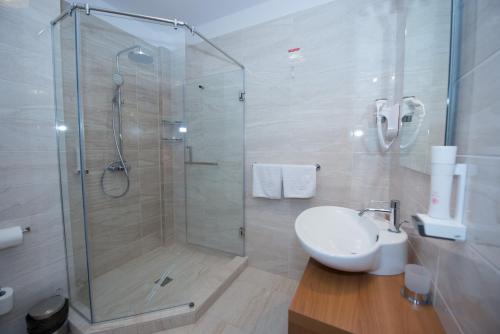 a bathroom with a shower and a sink and a toilet at Hotel TTS**** Spa&Wellness Covasna in Covasna