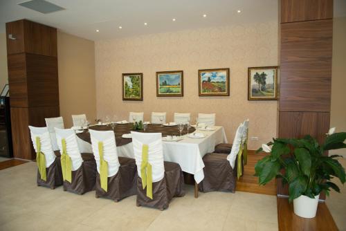a dining room with a long table with yellow and white chairs at Hotel TTS**** Spa&Wellness Covasna in Covasna