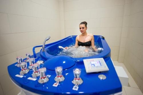 a woman sitting in a blue tub in a sink at Hotel TTS**** Spa&Wellness Covasna in Covasna