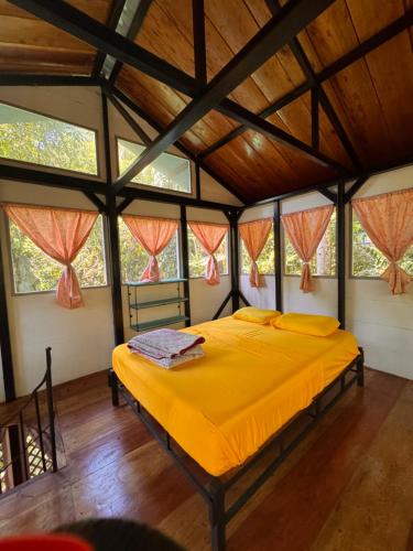 a bedroom with a yellow bed in a room with windows at Finca Tatin Hotel in Lámpara