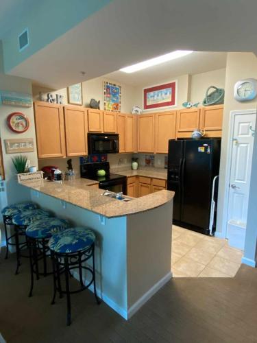 a kitchen with a black refrigerator and bar with stools at the palms of destin 2114 in Destin