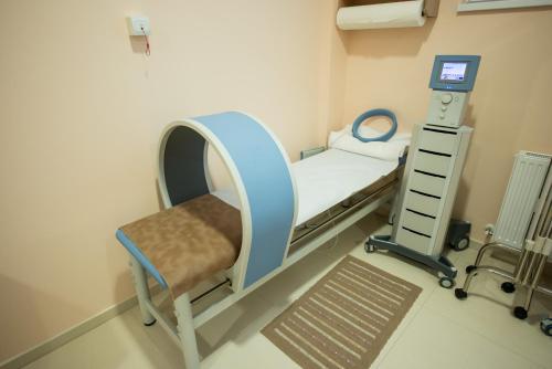 a hospital bed and a chair in a room at Hotel TTS**** Spa&Wellness Covasna in Covasna