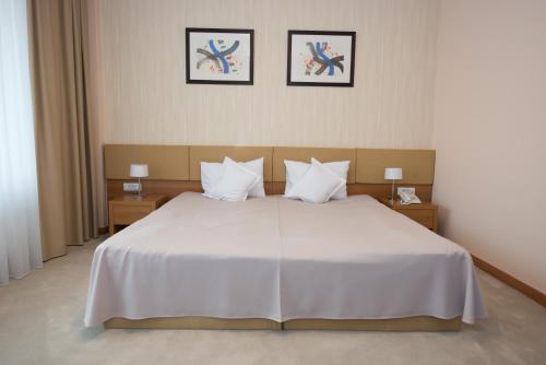 a bedroom with a white bed with two pictures on the wall at Hotel TTS**** Spa&Wellness Covasna in Covasna