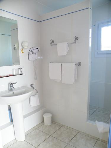 une salle de bain blanche avec un lavabo et une douche dans l'établissement Hôtel de L'Avenue, à Saintes