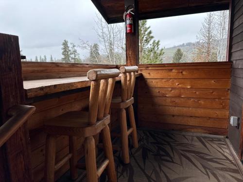 a porch with two wooden stools in front of a window at Chewuch Inn & Cabins in Winthrop