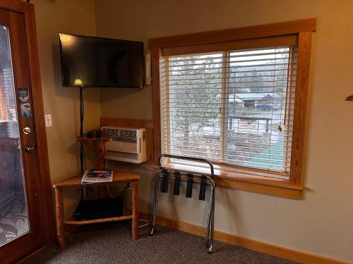a room with a window and a television and a table at Chewuch Inn & Cabins in Winthrop