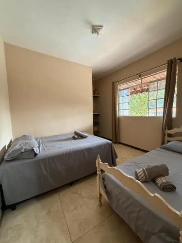 a bedroom with two beds and a window at Sitio descanso da Serra in Jaboticatubas